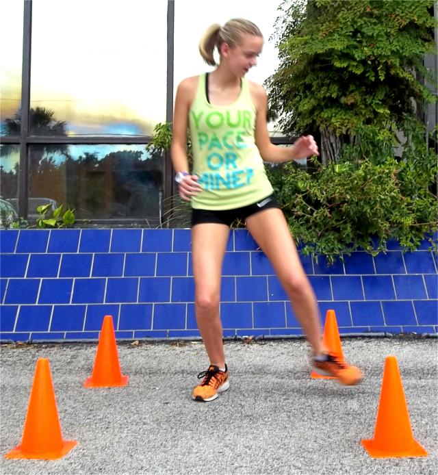 Young Woman running between cones.