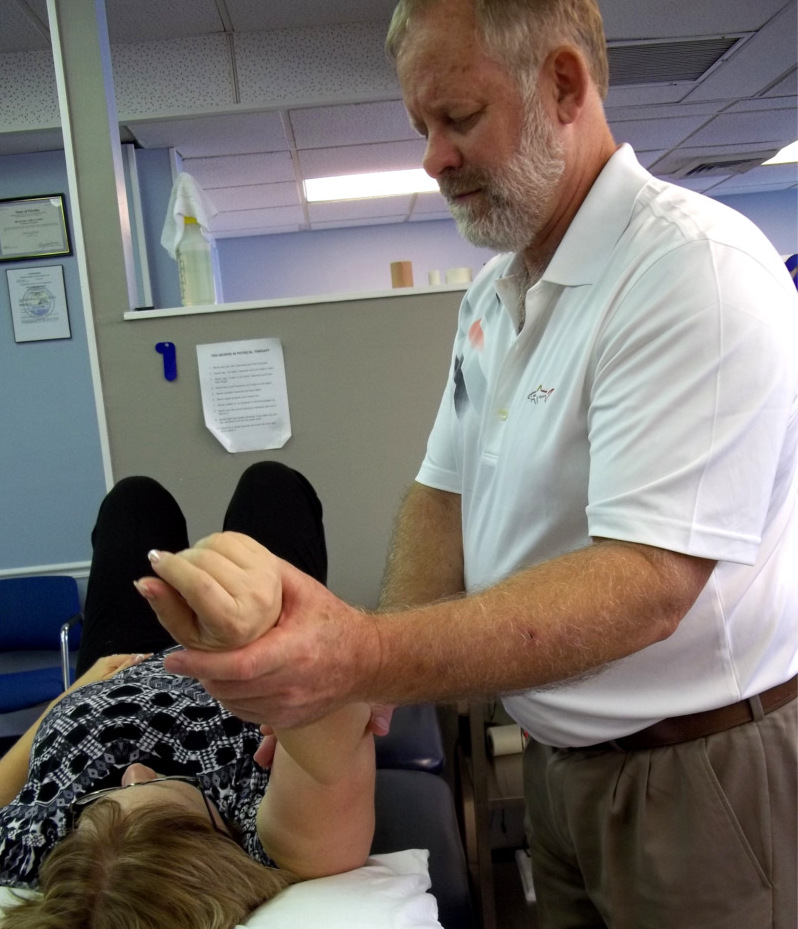 Therapist Holding Patient Arm with Two hands, Gentle moving arm over patient head while patient is lying down.