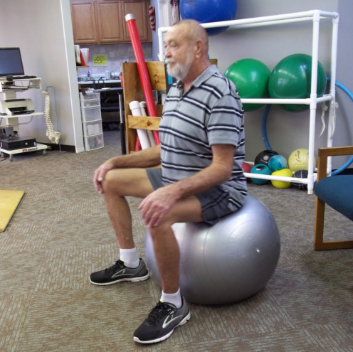 Man sitting on Large Therapy Ball, Sitting Tall with Hands on Knees, and Feet on Floor. Core and Back Strengthening